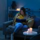 Woman sitting on a couch using a torch to read in a dark home during load shedding in South Africa, highlighting the need for a reliable inverter setup